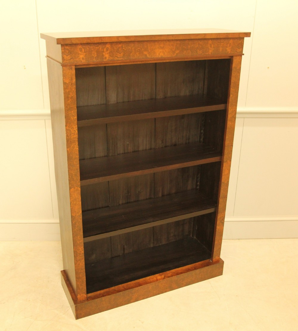 A Victorian open bookcase featuring faux burr walnut outer framing, dark interior shelves, and a solid plinth base. View VI