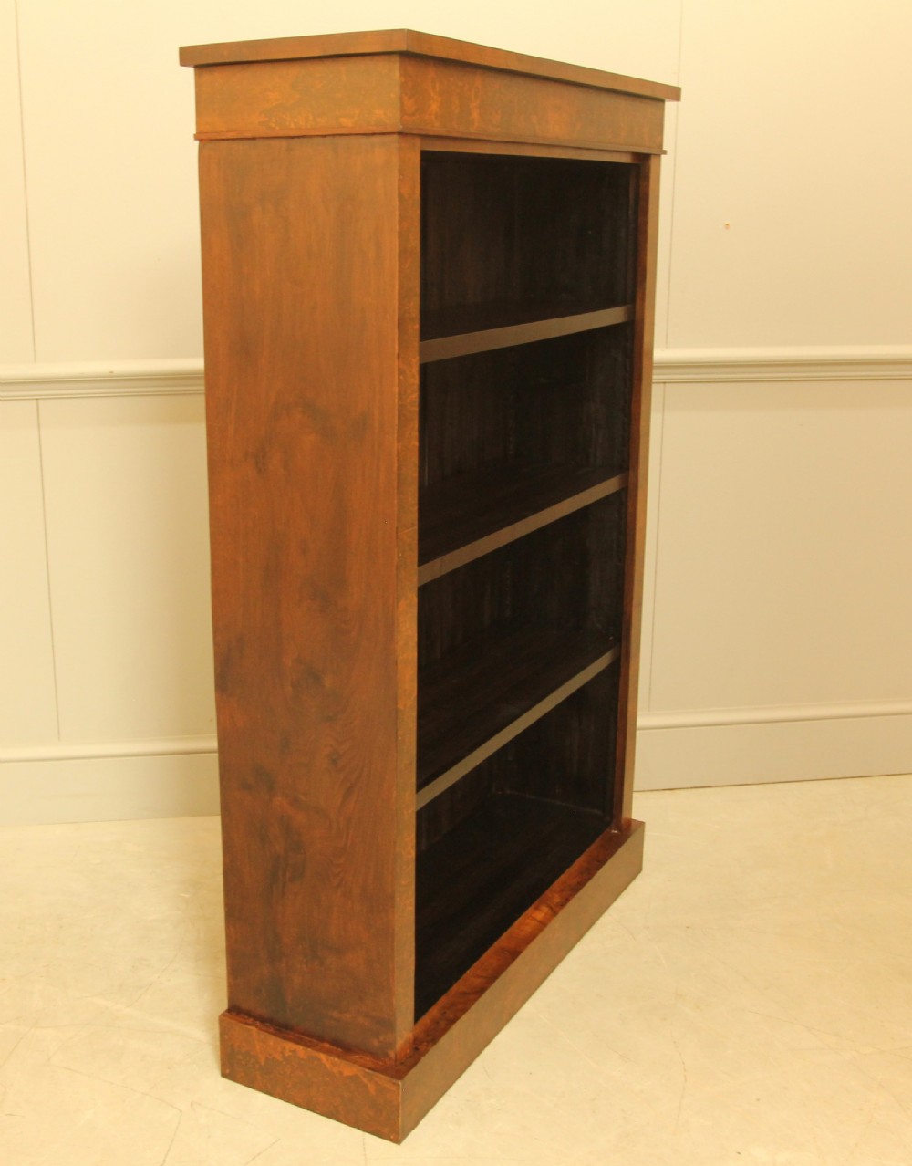 A Victorian open bookcase featuring faux burr walnut outer framing, dark interior shelves, and a solid plinth base. View VII