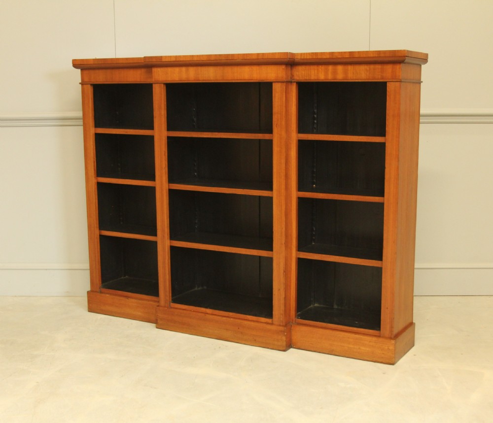 A low Victorian mahogany breakfront open bookcase featuring three sections with adjustable shelving on a solid plinth base.