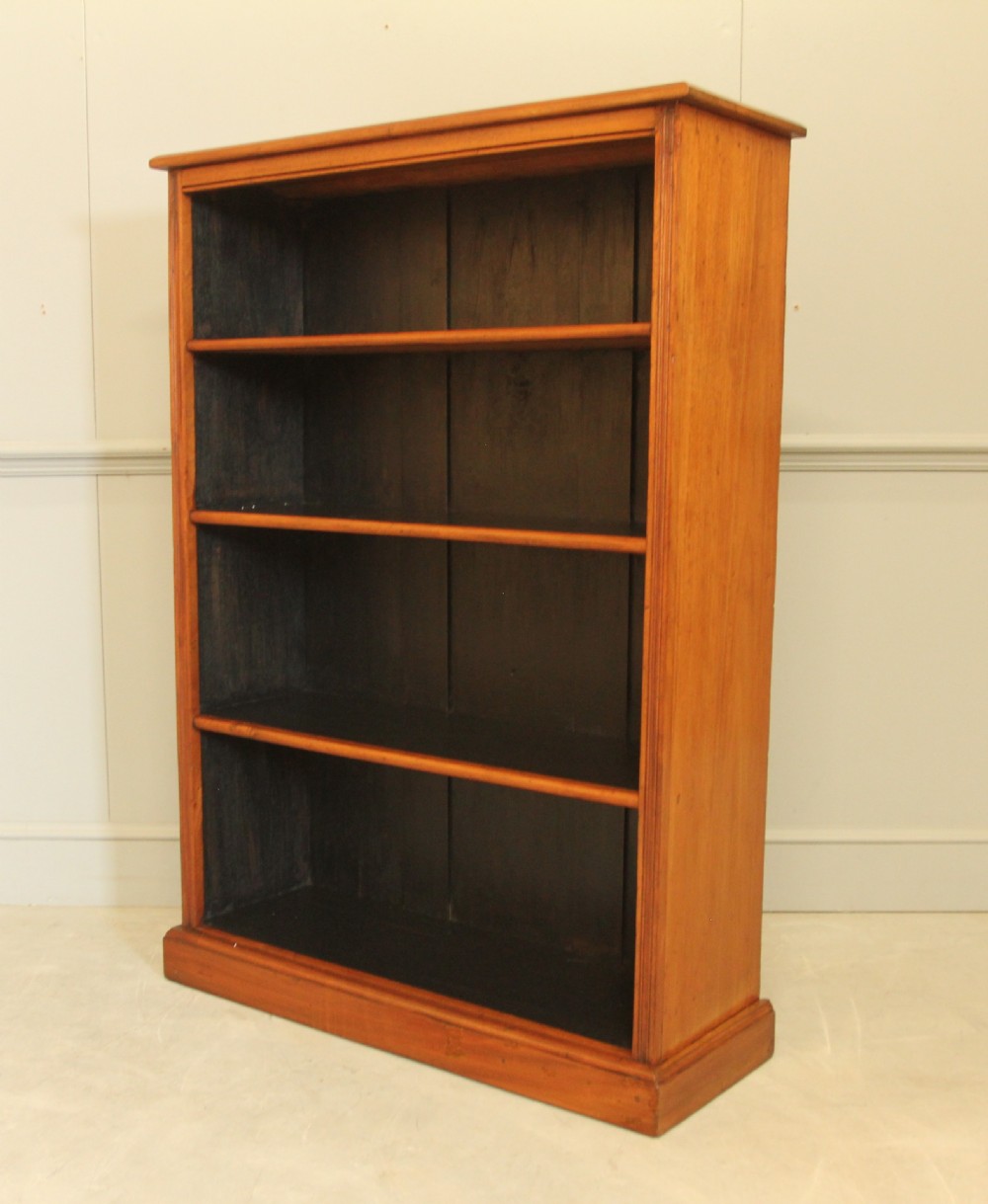 A tall open-front mahogany bookcase featuring four wide shelves, a moulded top cornice, dark backboards, and a solid plinth base. View V