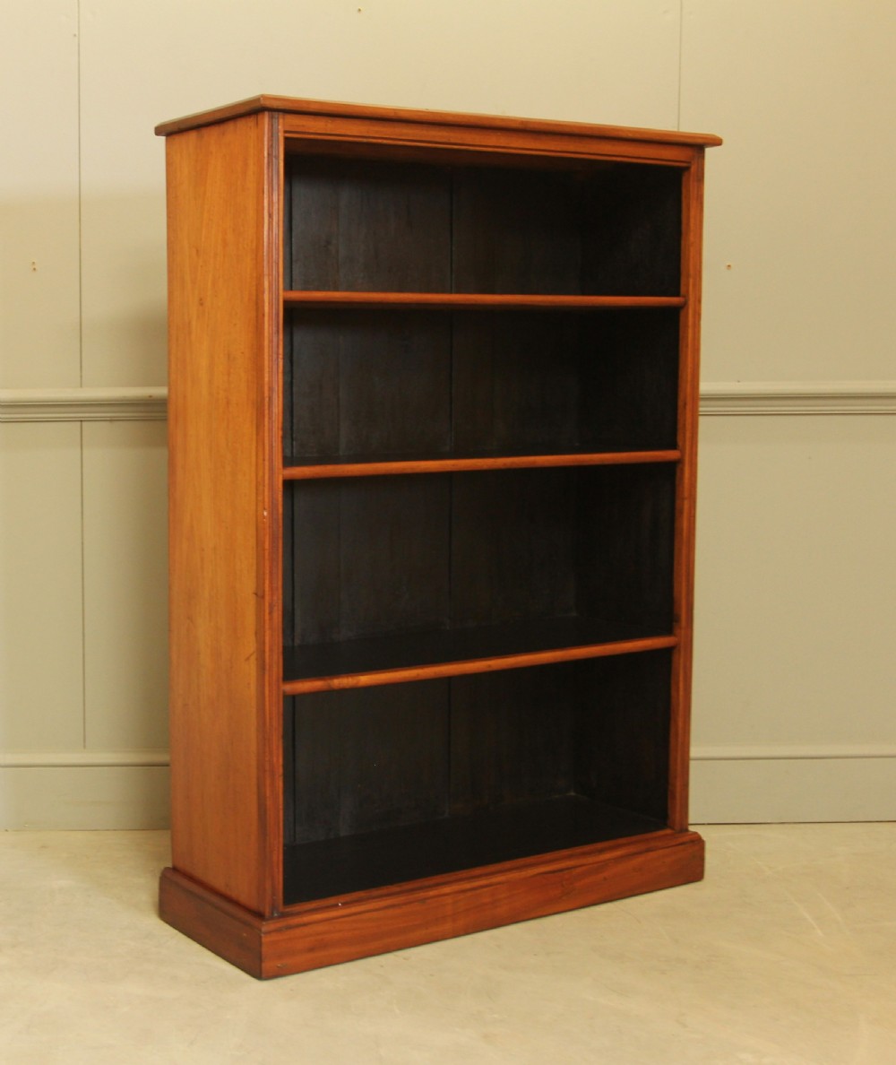 A tall open-front mahogany bookcase featuring four wide shelves, a moulded top cornice, dark backboards, and a solid plinth base. View VI