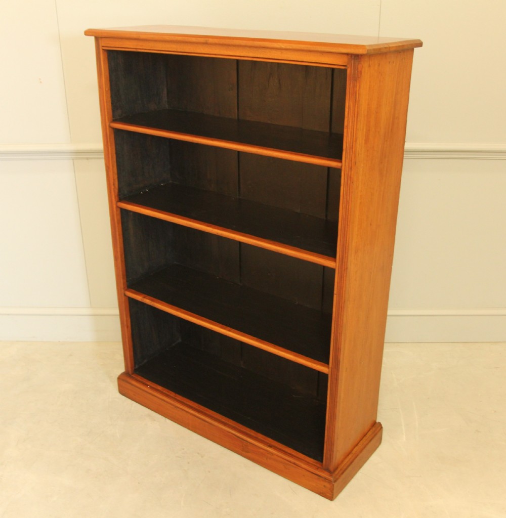 A tall open-front mahogany bookcase featuring four wide shelves, a moulded top cornice, dark backboards, and a solid plinth base. View VII