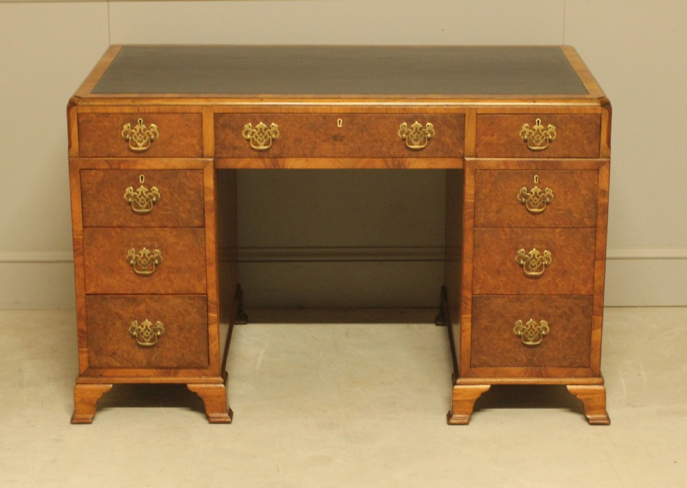 An antique burr walnut pedestal desk with a dark leather inset top, brass drop handles, and bracket feet. View II