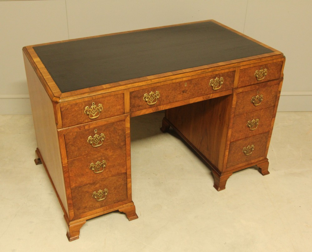 An antique burr walnut pedestal desk with a dark leather inset top, brass drop handles, and bracket feet. View III