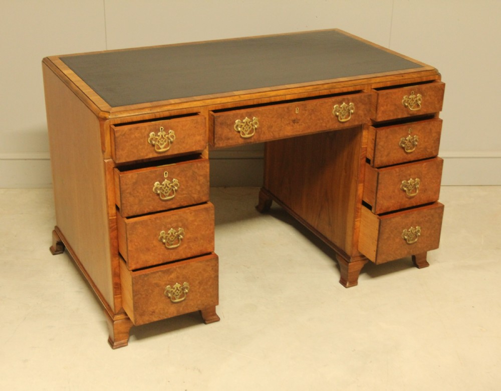 An antique burr walnut pedestal desk with a dark leather inset top, brass drop handles, and bracket feet. View V
