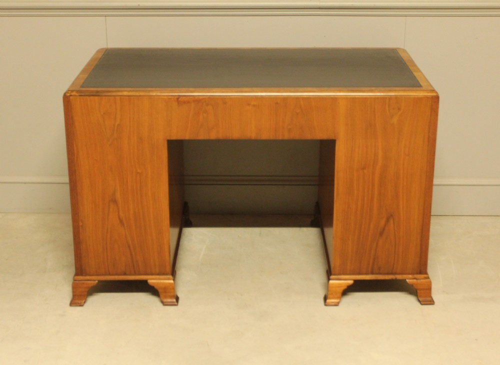 An antique burr walnut pedestal desk with a dark leather inset top, brass drop handles, and bracket feet. View X