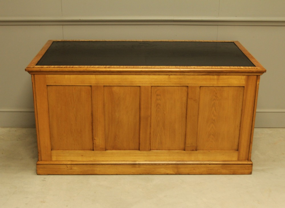 A late Victorian solid ash pedestal writing desk featuring nine drawers with brass drop handles and a dark inset top. View X