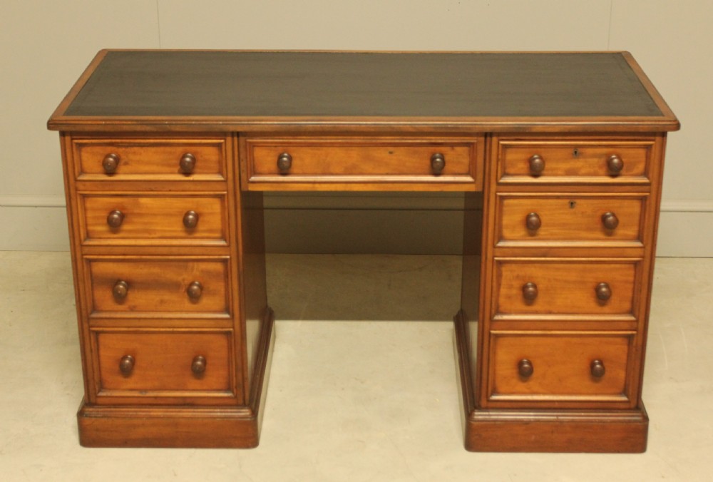 A Victorian mahogany pedestal desk featuring nine drawers with turned wooden handles and a dark leather inset writing surface. View II