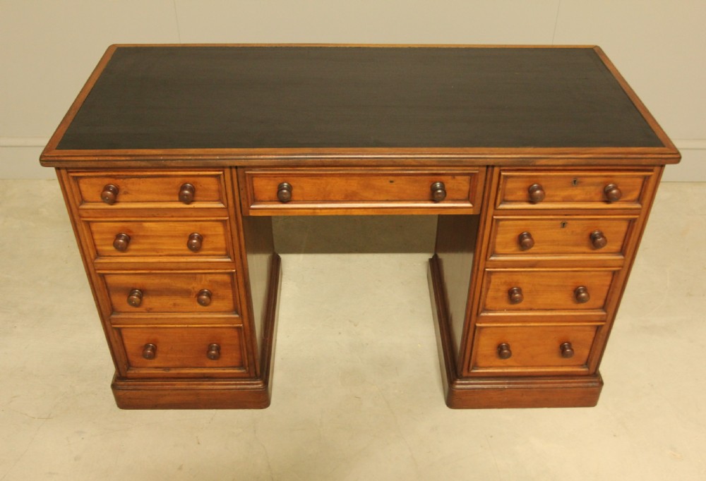 A Victorian mahogany pedestal desk featuring nine drawers with turned wooden handles and a dark leather inset writing surface. View III