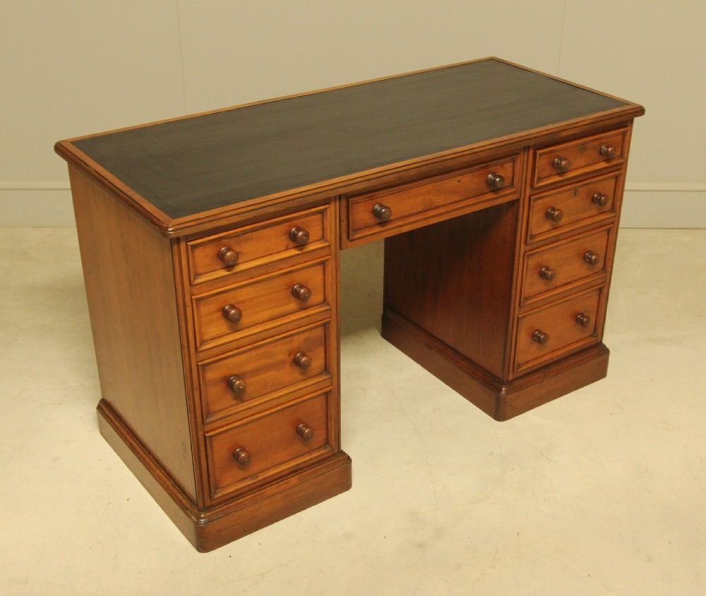 A Victorian mahogany pedestal desk featuring nine drawers with turned wooden handles and a dark leather inset writing surface. View V