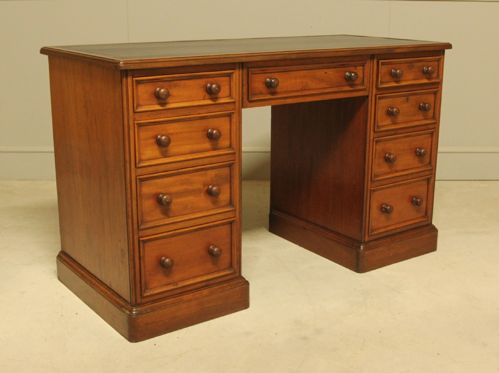 A Victorian mahogany pedestal desk featuring nine drawers with turned wooden handles and a dark leather inset writing surface. View VI