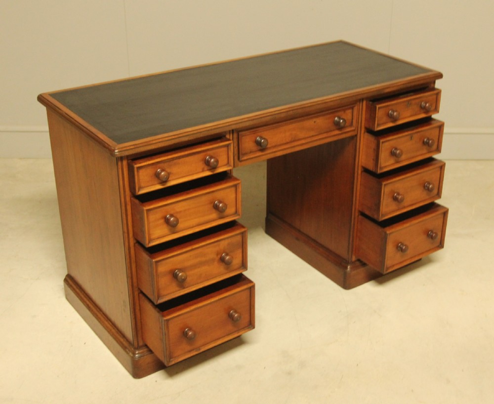 A Victorian mahogany pedestal desk featuring nine drawers with turned wooden handles and a dark leather inset writing surface. View VII