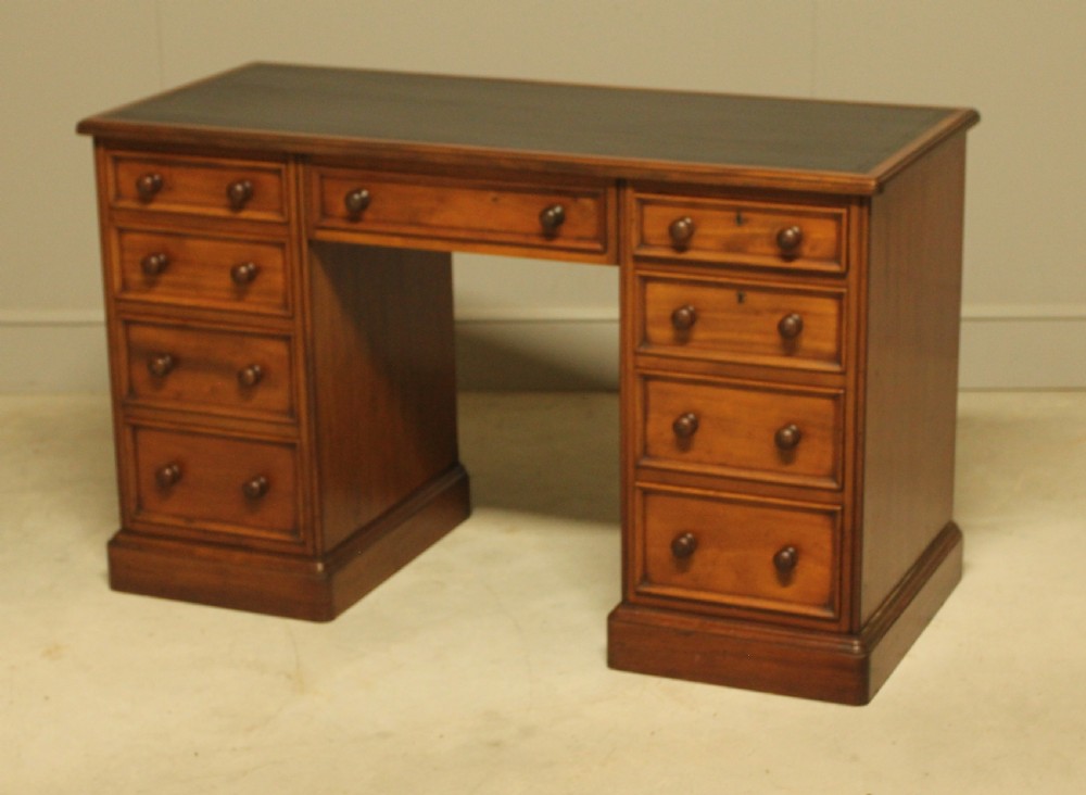 A Victorian mahogany pedestal desk featuring nine drawers with turned wooden handles and a dark leather inset writing surface. View VIII