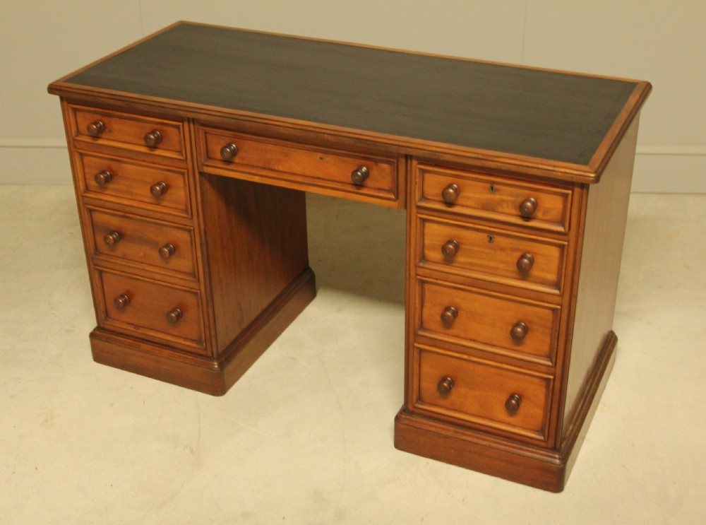 A Victorian mahogany pedestal desk featuring nine drawers with turned wooden handles and a dark leather inset writing surface. View IX