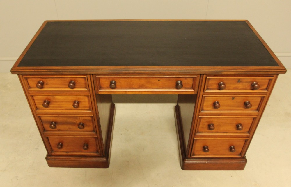 A Victorian mahogany pedestal desk featuring nine drawers with turned wooden handles and a dark leather inset writing surface. View X