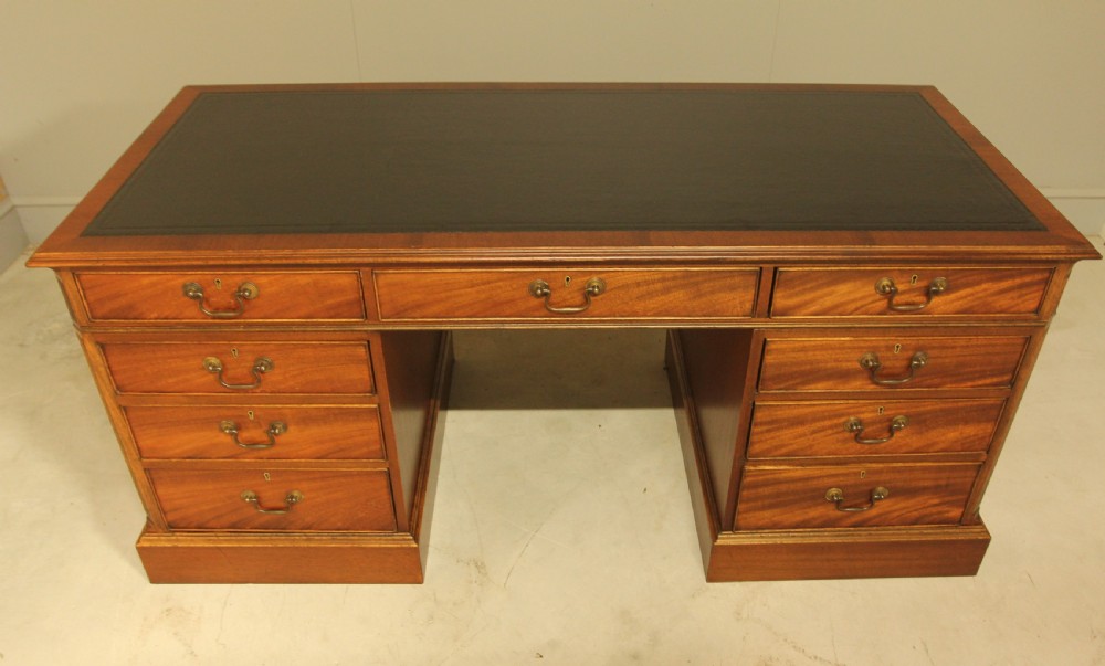 An early 20th-century twin pedestal desk crafted from curl mahogany with a dark leather inset top and brass swan-neck handles. View II