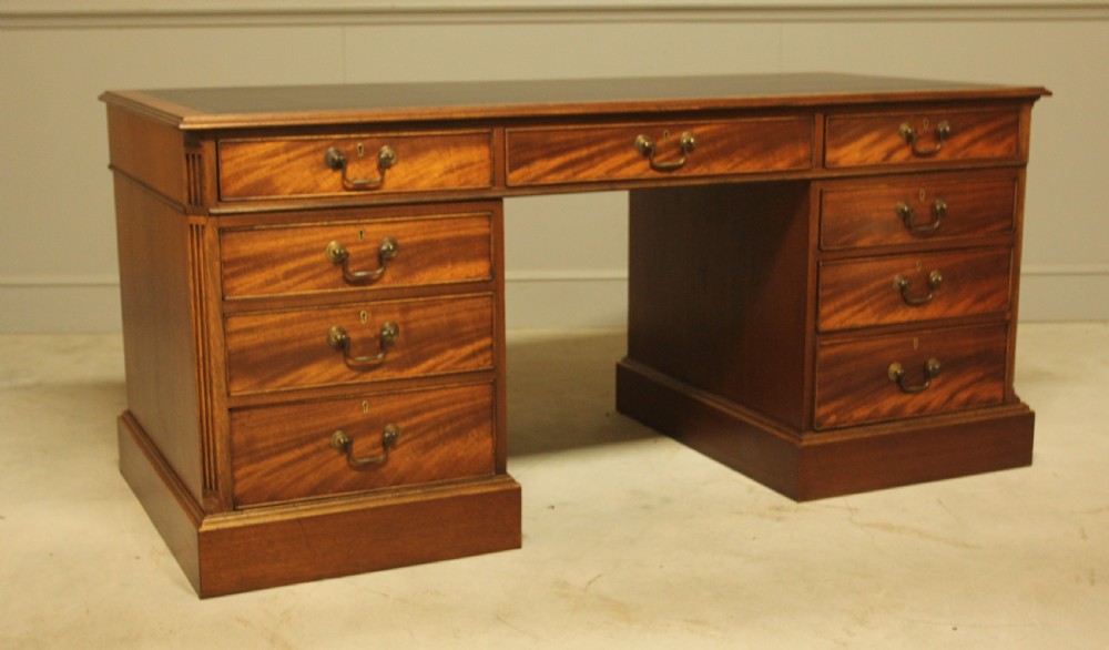 An early 20th-century twin pedestal desk crafted from curl mahogany with a dark leather inset top and brass swan-neck handles. View VI