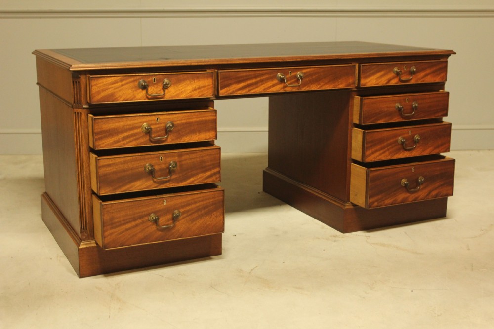 An early 20th-century twin pedestal desk crafted from curl mahogany with a dark leather inset top and brass swan-neck handles. View VII