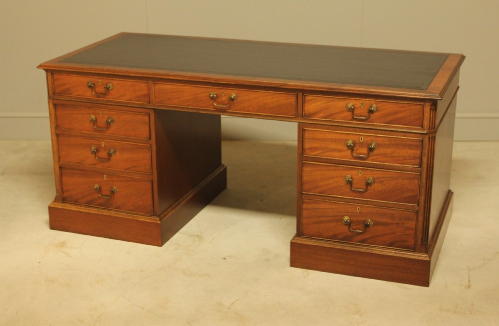 An early 20th-century twin pedestal desk crafted from curl mahogany with a dark leather inset top and brass swan-neck handles. View VIII