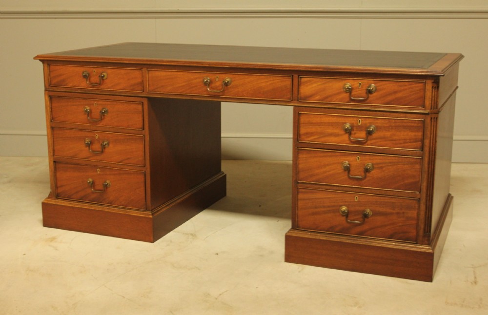 An early 20th-century twin pedestal desk crafted from curl mahogany with a dark leather inset top and brass swan-neck handles. View IX