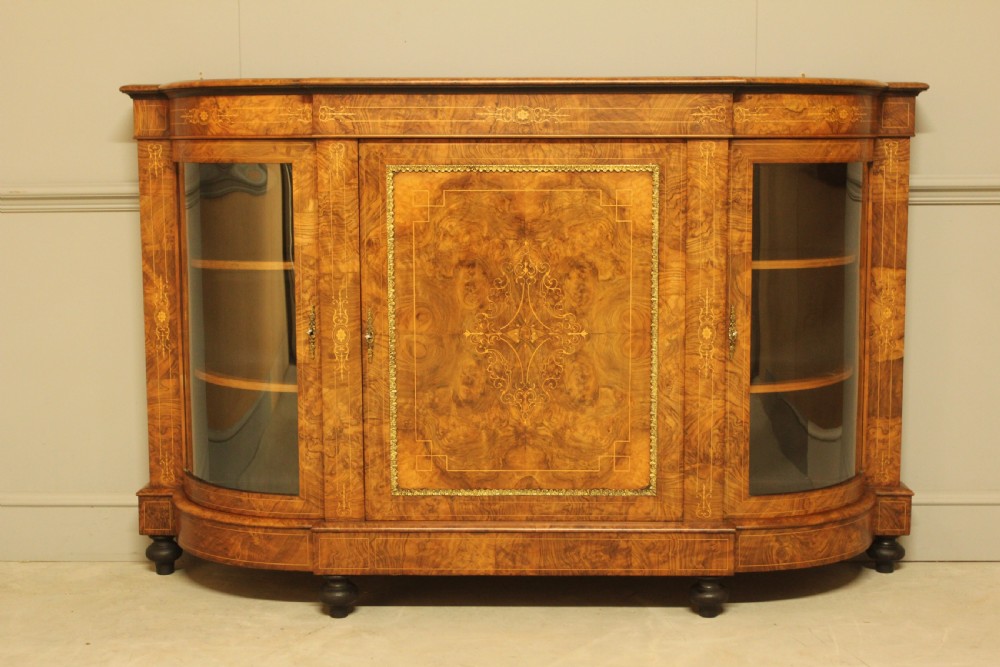 A Victorian burr walnut credenza featuring a central inlaid panel door flanked by two curved glass display doors with brass trim.