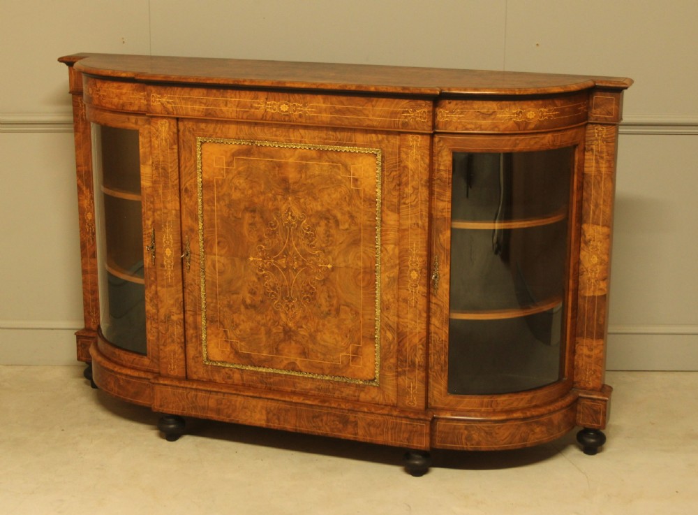 A Victorian burr walnut credenza featuring a central inlaid panel door flanked by two curved glass display doors with brass trim. View VII