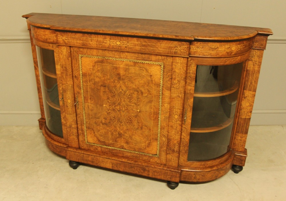 A Victorian burr walnut credenza featuring a central inlaid panel door flanked by two curved glass display doors with brass trim. View IX