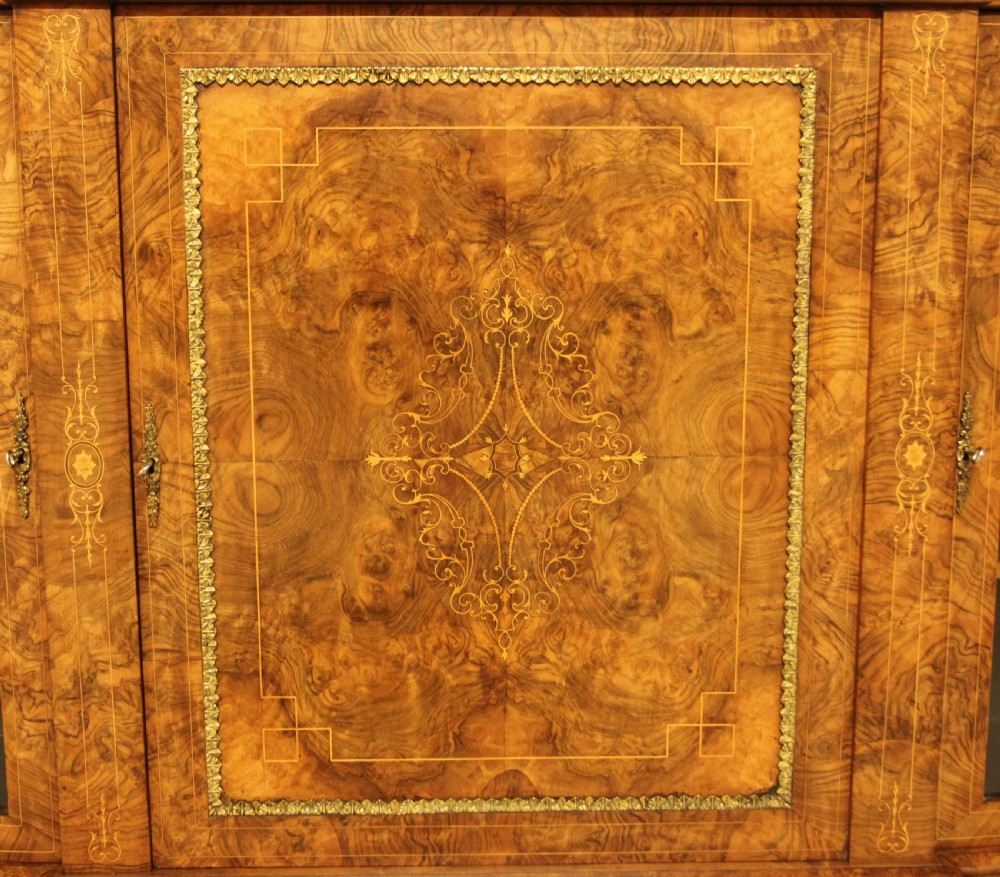 A Victorian burr walnut credenza featuring a central inlaid panel door flanked by two curved glass display doors with brass trim. View XI