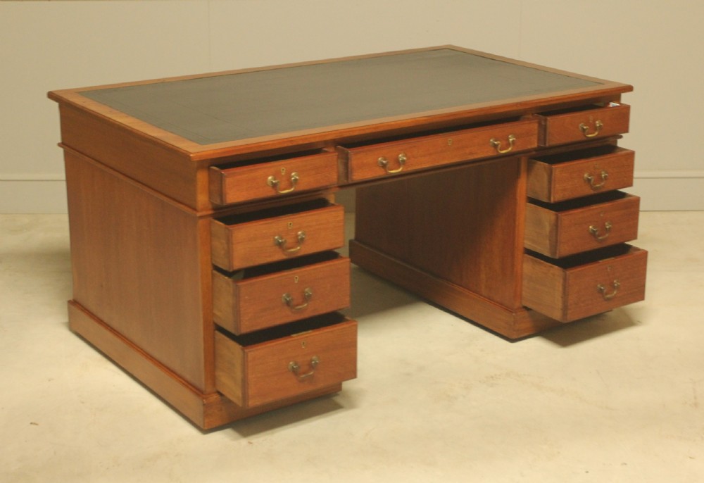 An early 20th-century mahogany pedestal writing desk featuring a dark leather inset top and nine drawers with brass swan-neck handles. View IV