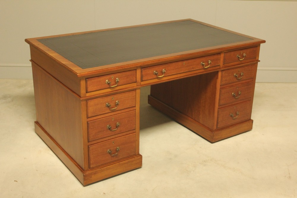 An early 20th-century mahogany pedestal writing desk featuring a dark leather inset top and nine drawers with brass swan-neck handles. View V