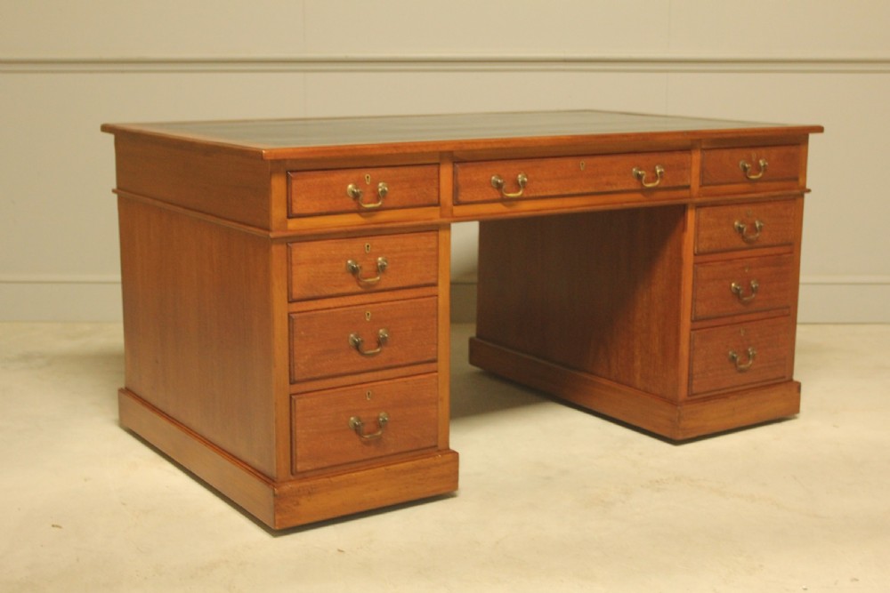An early 20th-century mahogany pedestal writing desk featuring a dark leather inset top and nine drawers with brass swan-neck handles. View VI