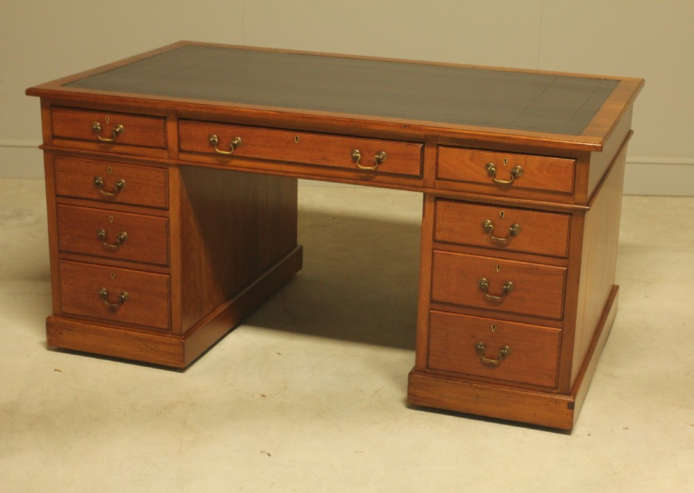 An early 20th-century mahogany pedestal writing desk featuring a dark leather inset top and nine drawers with brass swan-neck handles. View VII