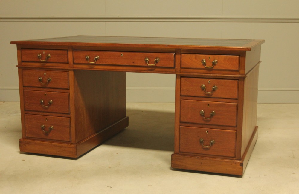 An early 20th-century mahogany pedestal writing desk featuring a dark leather inset top and nine drawers with brass swan-neck handles. View VIII