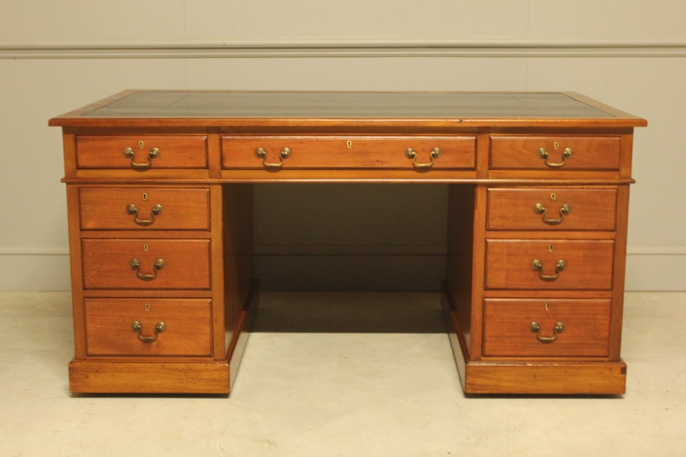 An early 20th-century mahogany pedestal writing desk featuring a dark leather inset top and nine drawers with brass swan-neck handles. View X