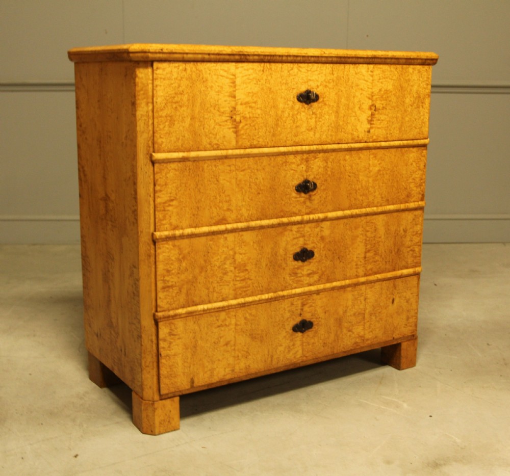 A nineteenth-century Swedish chest of drawers featuring four drawers crafted from light golden masur birch with dark keyhole escutcheons. View V