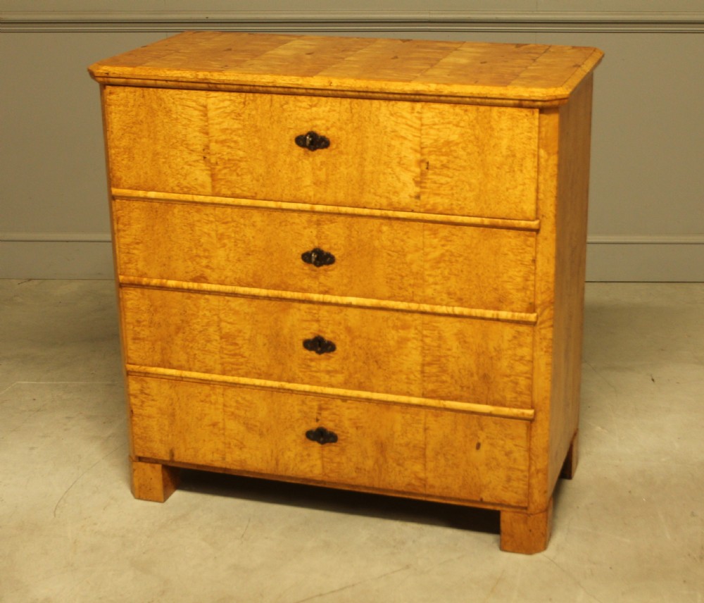 A nineteenth-century Swedish chest of drawers featuring four drawers crafted from light golden masur birch with dark keyhole escutcheons. View VI