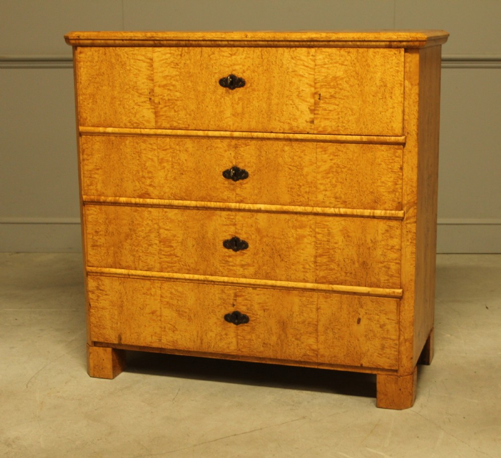 A nineteenth-century Swedish chest of drawers featuring four drawers crafted from light golden masur birch with dark keyhole escutcheons. View VII