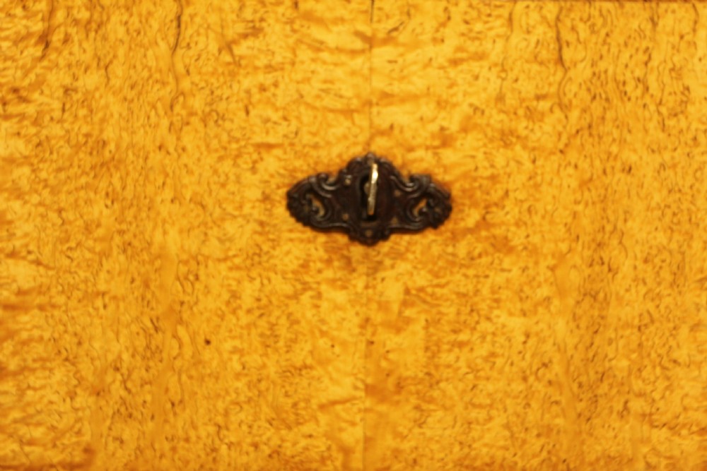 A nineteenth-century Swedish chest of drawers featuring four drawers crafted from light golden masur birch with dark keyhole escutcheons. View X