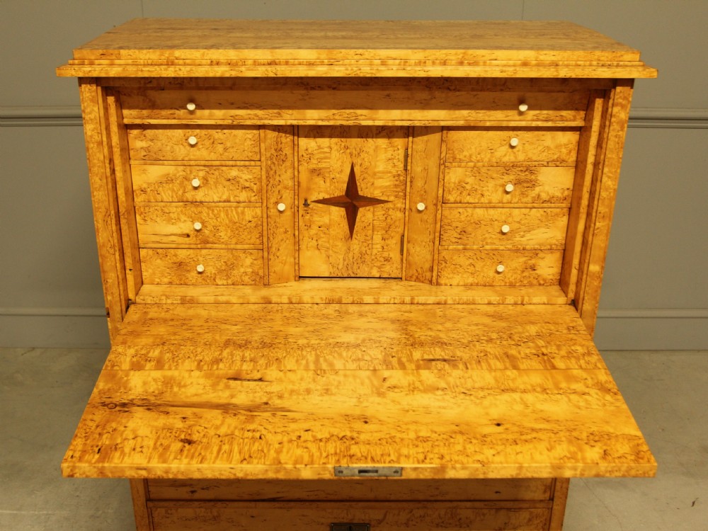A 19th-century Swedish Masur birch secretaire desk featuring a fall-front top compartment above three wide drawers with brass handles. View IX