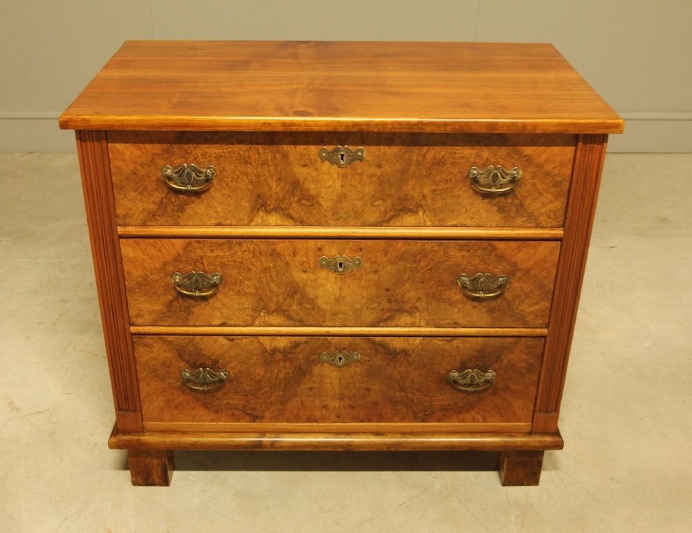 An early 20th-century Swedish chest of drawers featuring three full-width drawers with rich burr walnut veneer, brass bail handles, and keyhole escutcheons. View II
