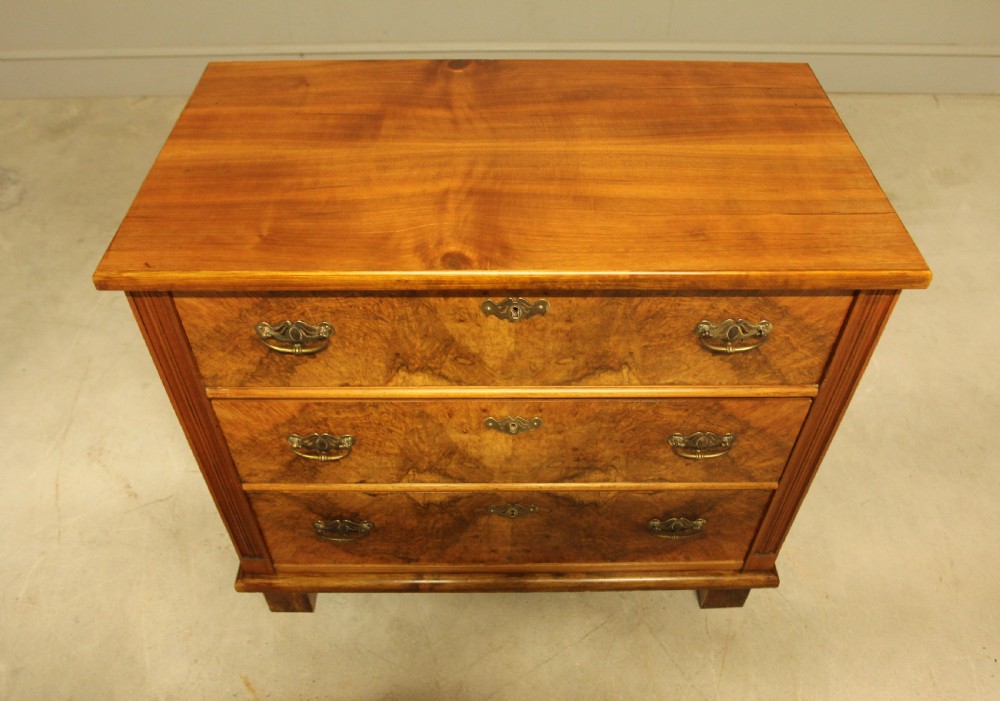 An early 20th-century Swedish chest of drawers featuring three full-width drawers with rich burr walnut veneer, brass bail handles, and keyhole escutcheons. View III