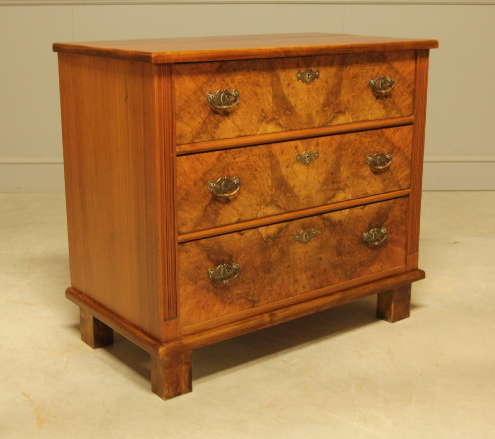 An early 20th-century Swedish chest of drawers featuring three full-width drawers with rich burr walnut veneer, brass bail handles, and keyhole escutcheons. View IV