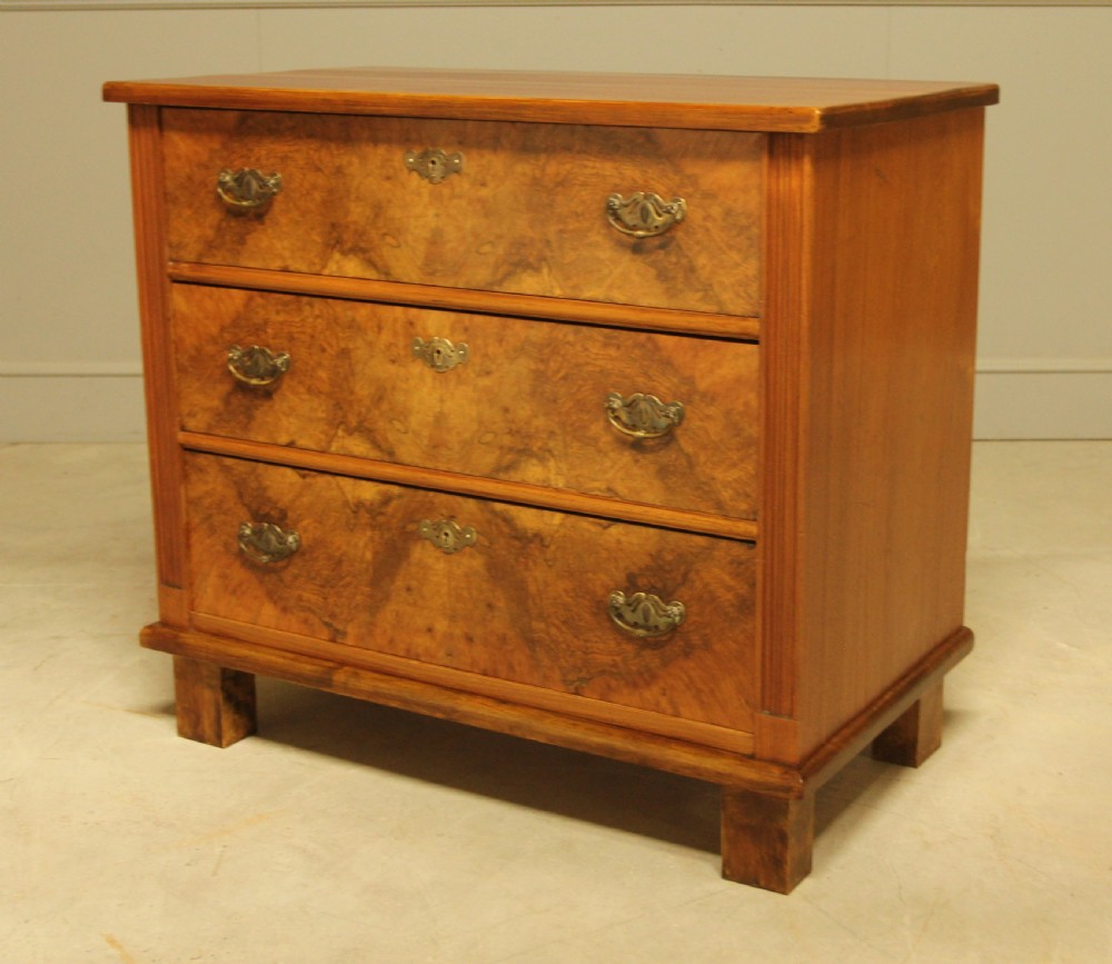 An early 20th-century Swedish chest of drawers featuring three full-width drawers with rich burr walnut veneer, brass bail handles, and keyhole escutcheons. View VII