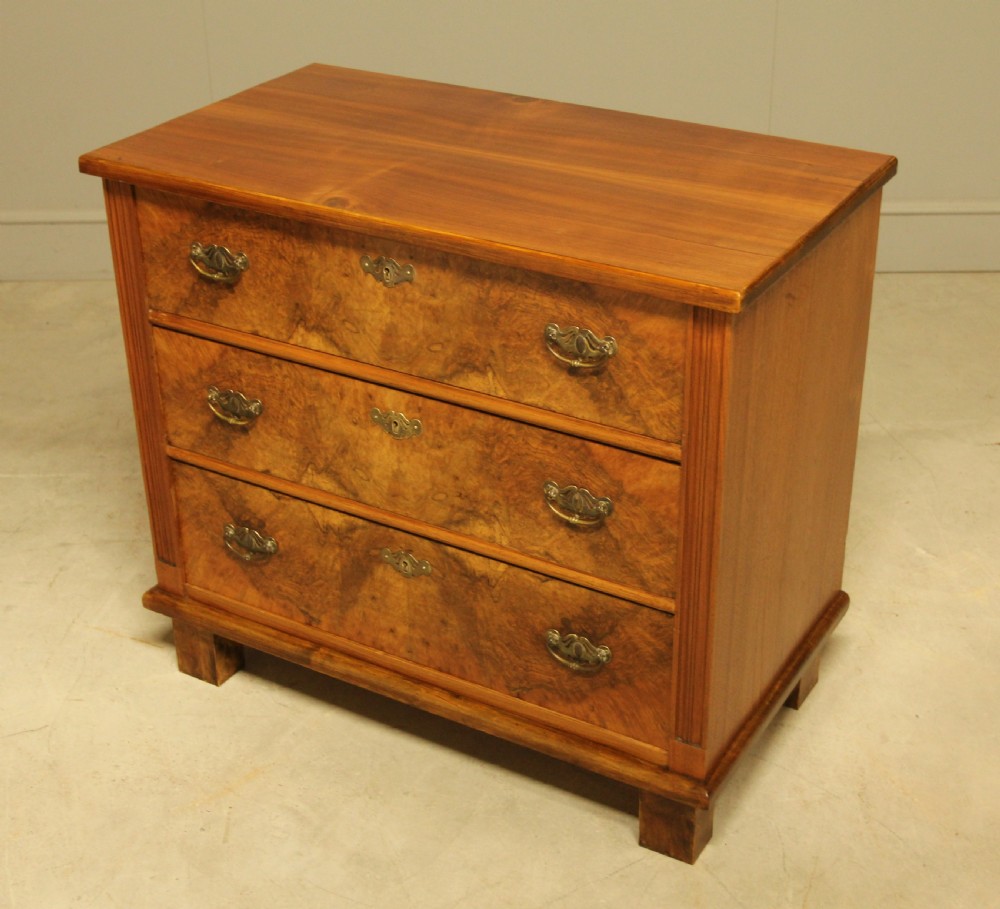 An early 20th-century Swedish chest of drawers featuring three full-width drawers with rich burr walnut veneer, brass bail handles, and keyhole escutcheons. View VIII
