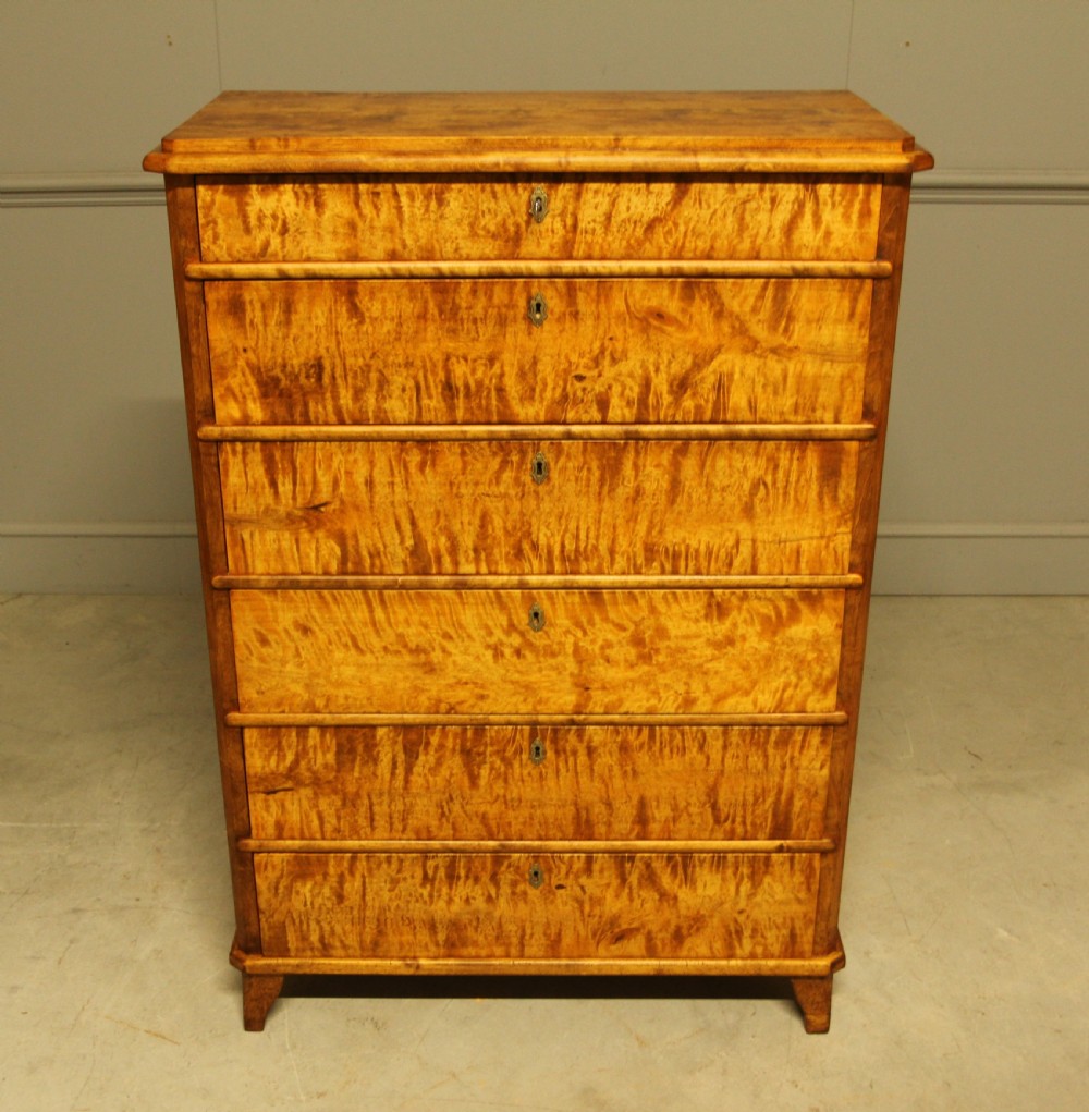 An early twentieth-century Swedish tall chest of drawers crafted in figured golden satin birch with six graduated drawers and brass escutcheons. View IV