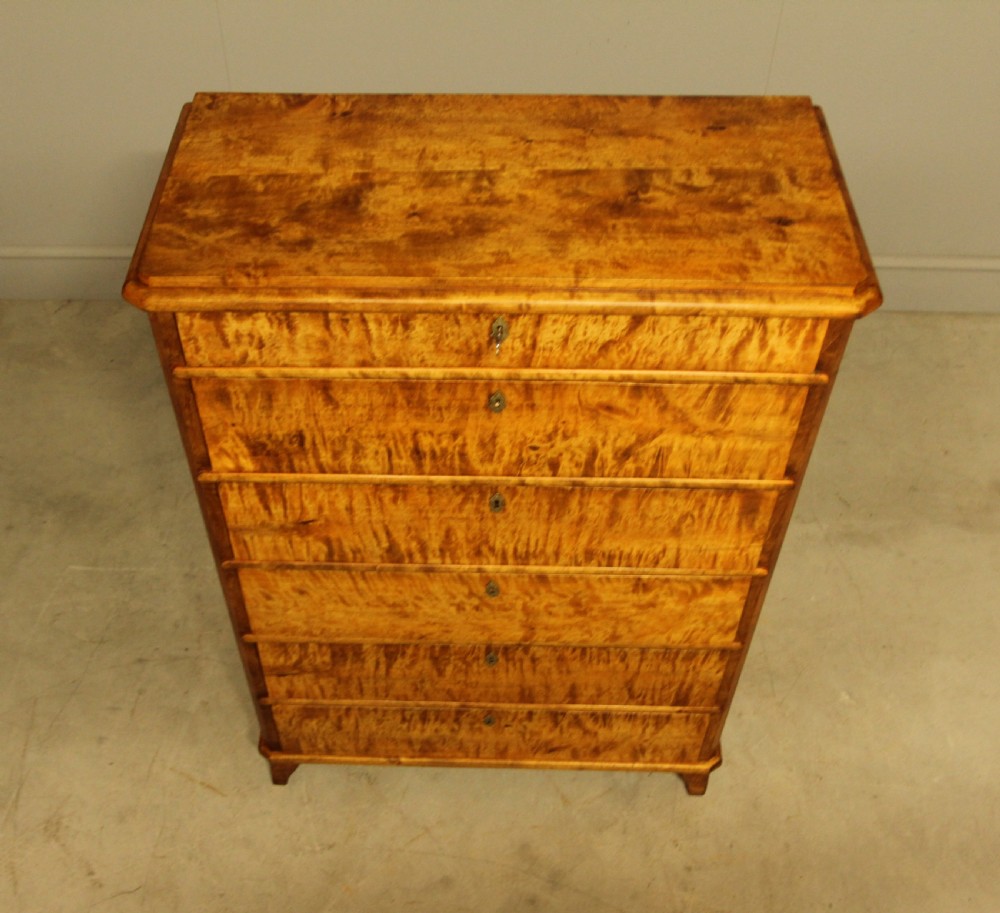 An early twentieth-century Swedish tall chest of drawers crafted in figured golden satin birch with six graduated drawers and brass escutcheons. View V