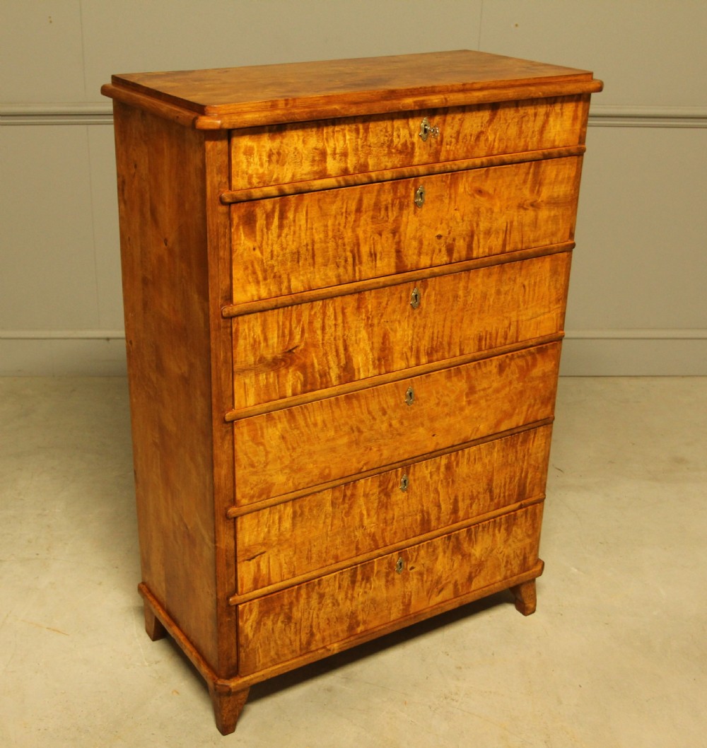 An early twentieth-century Swedish tall chest of drawers crafted in figured golden satin birch with six graduated drawers and brass escutcheons. View VI