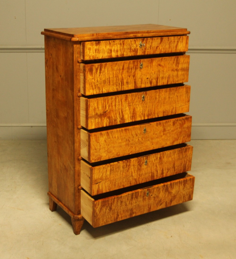 An early twentieth-century Swedish tall chest of drawers crafted in figured golden satin birch with six graduated drawers and brass escutcheons. View VII