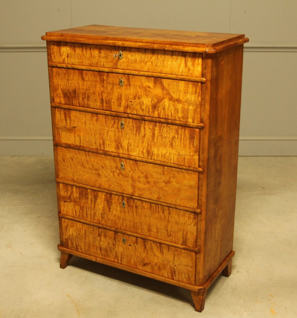An early twentieth-century Swedish tall chest of drawers crafted in figured golden satin birch with six graduated drawers and brass escutcheons. View VIII
