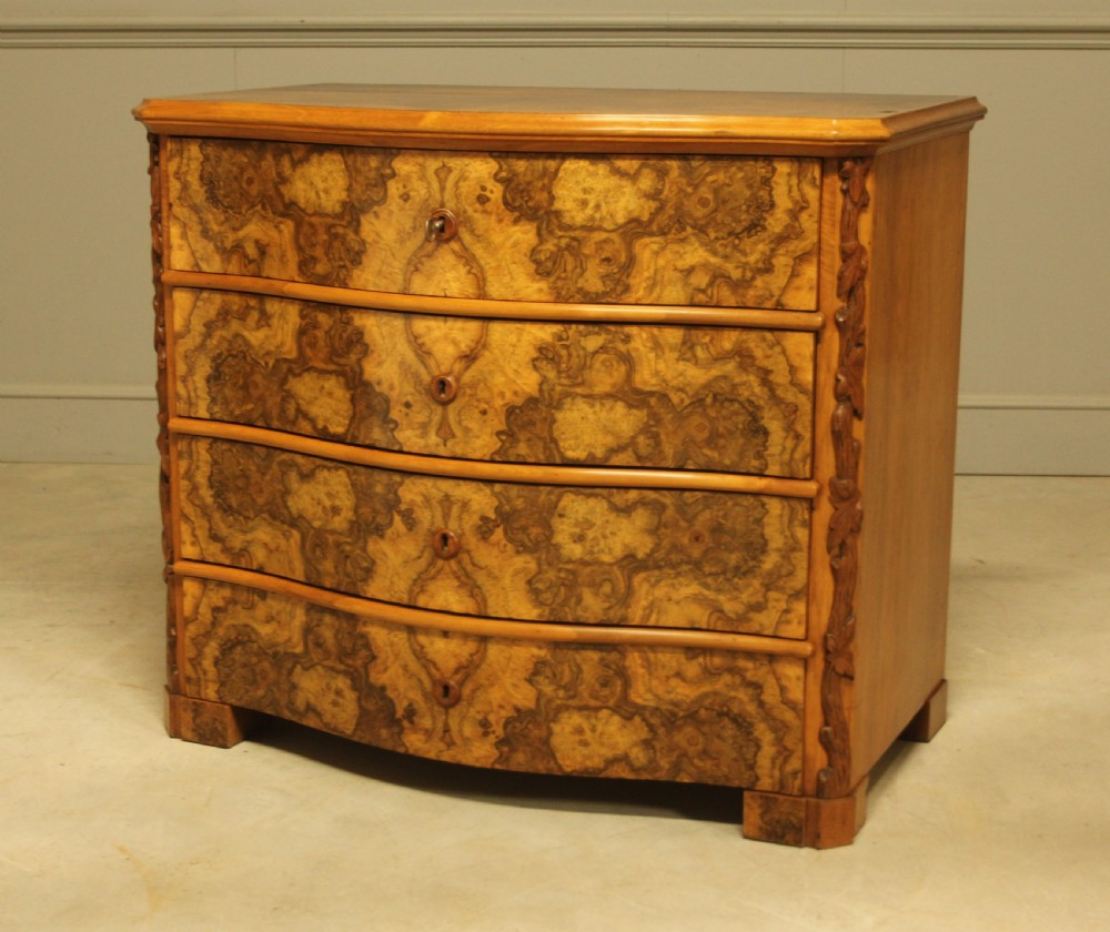A Neo-Rococo Swedish chest of drawers featuring a serpentine front, highly figured burr walnut veneer, carved foliate corner pilasters, and four full-width drawers. View III